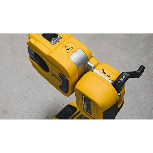 Close-up of a DEWALT DCE154N yellow cordless photography tool, showing the control lever and various markings on the housing, placed on a neutral surface.